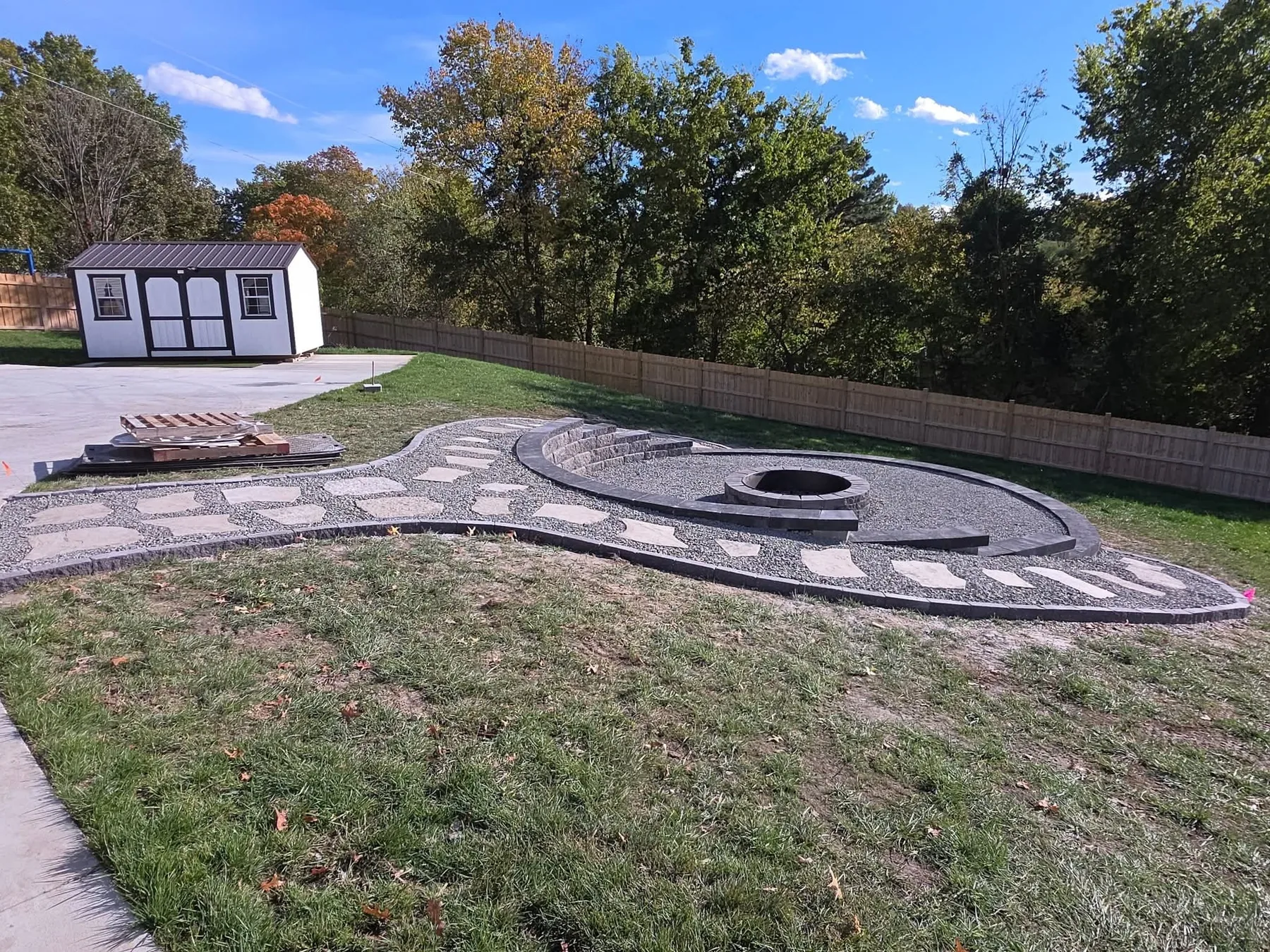 Finished backyard hardscape with a gravel firepit area, paver path, and clean edging